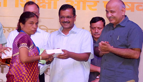 Arvind Kejriwal giving a smartphone to an Aanganwadi worker